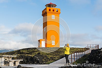 SNAEFELLSNES,Woman in yellow raincoat taking picture of Svortuloft Lighthouse, Snaefellsnes peninsula, Iceland Stock Photo