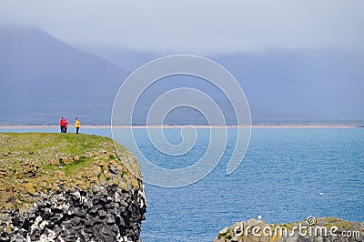 Unidentified tourists standing at the cliff near Gatklettur Stone Arch at Snaefellsnes Peninsula, Iceland Editorial Stock Photo