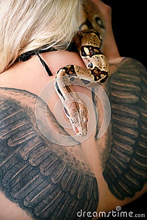 Snake on female shoulder and back, part woman body. Boa constrictor snake crawling per womanâ€™s back, shoulder, tattoo. Stock Photo