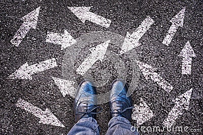 Sneaker shoes and arrows pointing in different directions on asphalt, choice concept Stock Photo