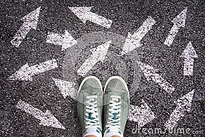 Sneaker shoes and arrows pointing in different directions on asphalt, choice concept Stock Photo