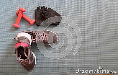 Sneakers ready to training at home, making exercise in a fitness class with muscular equipment. Jumping rope, pink dumbbells and Stock Photo