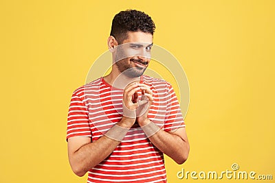 Sneaky cunful man with beard in striped red t-shirt drumming fingers planning devious pranks, thinking over revenge plan, scheming Stock Photo