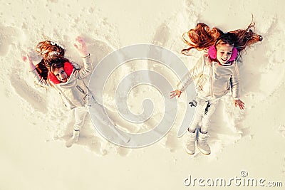 Snow angels made by a kids in the snow. Smiling children lying on snow with copy space. Funny kids making snow angel Stock Photo