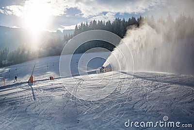 Snow cannons working on ski slope in Alps at sunny day Editorial Stock Photo