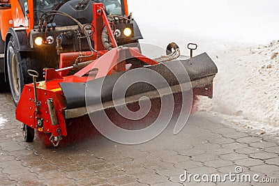 Snow cleaning. Snow removal tractor clearing snow from pavement with special round spinning brush, Stock Photo