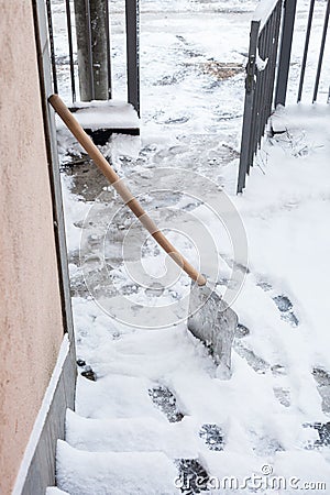 Snow cleaning shovel lean on house wall ready for cleaning entrance and stairs cold winter Stock Photo