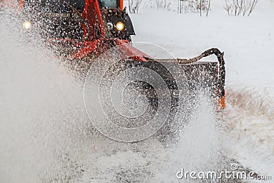 Snow cleaning. Snow removal tractor clearing snow from pavement with special round spinning brush, Stock Photo