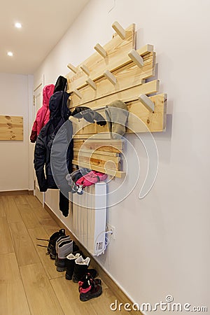 Snow clothes hanging on a hanger on the wall and boots on the floor in the entrance hall of the holiday apartment Stock Photo