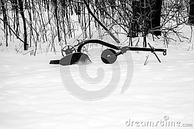Snow covered antique plow next to a Wisconsin forest in winter Stock Photo