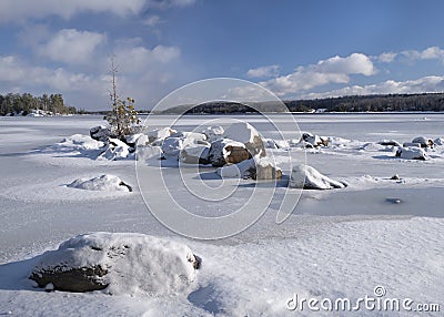 Snow covered granite boulders in frozen lake Stock Photo