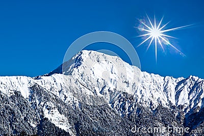 Snow-covered high mountain with sunny sky Stock Photo