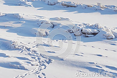 Snow-covered ice surface of the river on a winter day. Traces of people and animals. Light and shade. Stock Photo
