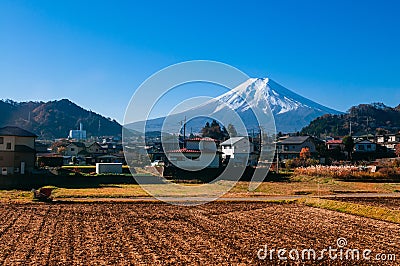 Snow covered Mount Fuji and local town along train route in Shimoyoshida - Fujiyoshida, Japan Stock Photo