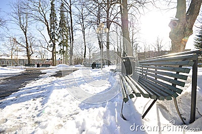 Snow-covered park with melted footpath. Beautiful winter landscape in the city. Decorative streetlamps and park benches in a row Stock Photo
