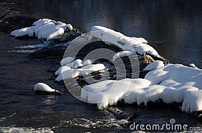 Snow Covered Rocks Forming Dam Across the Cold Winter River Stock Photo