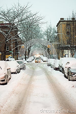 Snow-covered street and cars on a cold and dreary winter`s day in Harlem, New York, NY, USA Editorial Stock Photo