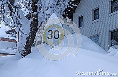 A snow-covered traffic sign with speed limit 30 in winter Stock Photo