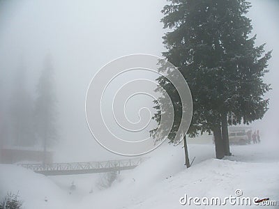 Snow covered winter landscape in thick fog. Winter resort with a bridge. People are going to the road at the car Stock Photo