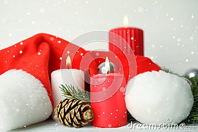 Snow falling on burning candles and festive decor against light background. Christmas eve Stock Photo