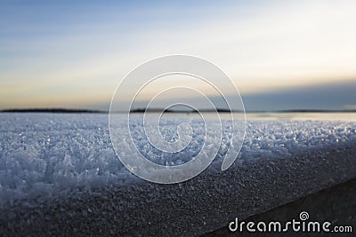 Snow frost abstract winter background close-up bokeh, Cold season rime ice crystals on wooden embankment of lake Malaren, evening Stock Photo