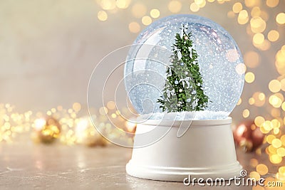 Snow globe with Christmas tree on marble table, space for text. Bokeh effect Stock Photo