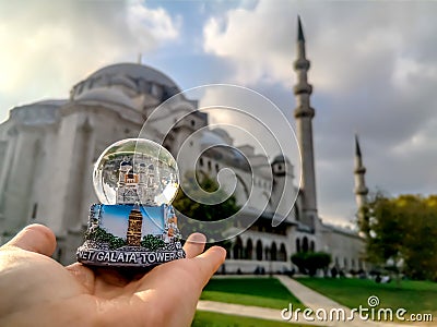 Snow globe with Istanbul in hand on a blurred background of the Suleymaniye Mosque. Souvenir from the Turkish tourist city, close- Stock Photo