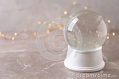 Snow globe on marble table against festive lights. Christmas season Stock Photo