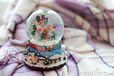 A snow globe with a snowman is standing on a plaid. Winter day Stock Photo