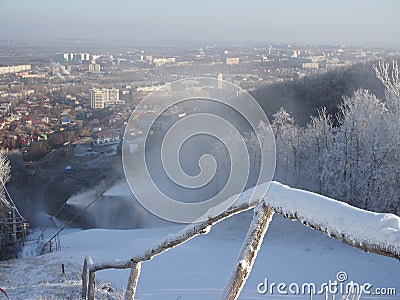 Snow gun making artificial snow in morning, on back fir forest. Snowmaking by water through snow cannon for snow cover Stock Photo