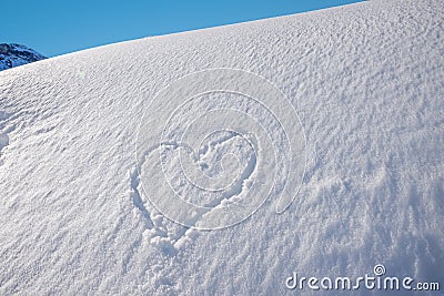 Snow heap with carved love heart, blue sky. mountain landscape Stock Photo