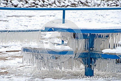 Icicles on blue park bench and table Stock Photo