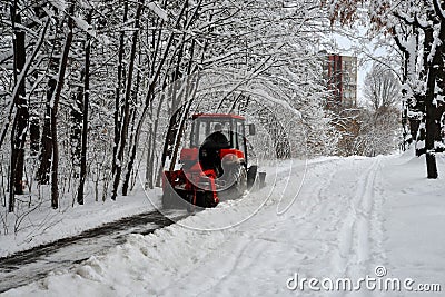 Snow machine, red tractor cleans the snow from the snow in the background of the forest. Stock Photo