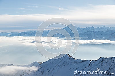 Snow mountains in backlight, bright sunny day winter on the Alps, high snowcapped mountain peaks, fog and clouds in the valleys be Stock Photo