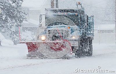 Snow plow with a red plow working in a blizzard Stock Photo