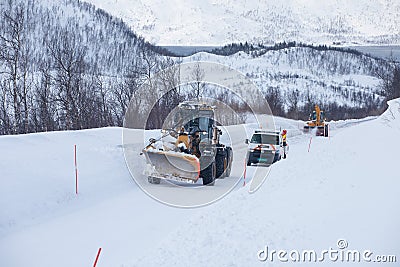 Snow plow truck clearing icy road after winter snowstorm blizzard for vehicle access Snow blower clears snow-covered streets Editorial Stock Photo