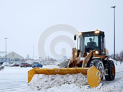 Snow removal machine clearing parking lot during snow storm Editorial Stock Photo