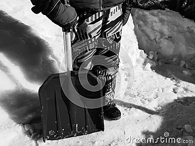 Snow shovel in the hands - the child cleans the snow in winter or spring Stock Photo