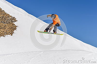 Snowboarder enjoying runs and jumps on spring`s last snow. Editorial Stock Photo