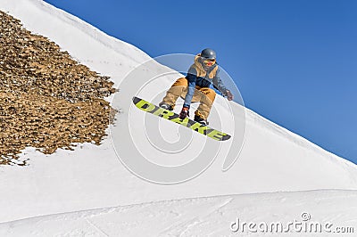 Snowboarder enjoying runs and jumps on spring`s last snow. Editorial Stock Photo