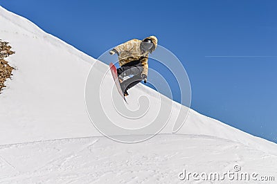 Snowboarder enjoying runs and jumps on spring`s last snow. Editorial Stock Photo