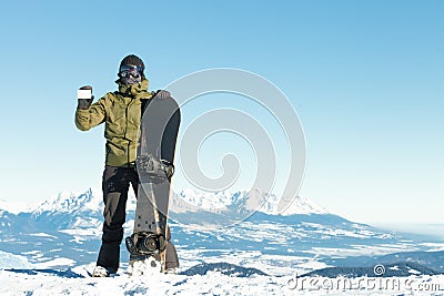 Snowboarder holding blank lift pass in one hand and snowboard in another with beautiful mountains on background Stock Photo