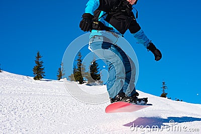 Snowboarder Jumping over Slope on Red Snowboard in the Mountains at Sunny Day. Extreme Snowboarding and Winter Sports Stock Photo