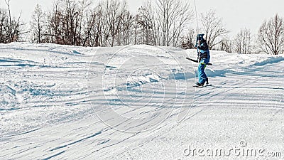 Snowboarder performs a nollie frontside 180 trick while climbing on a T-bar lift Stock Photo