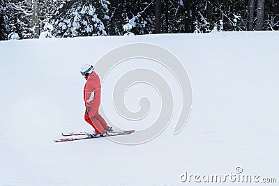 Snowboarder in red ski suit rises on lift up mountain slope. Ski sports in winter. Stock Photo