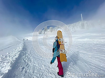 Snowboarder and skiers hike up a fog covered slope of a shut down ski resort. Stock Photo