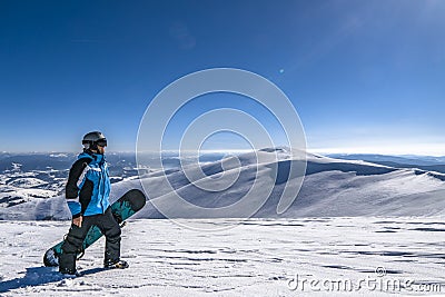 Snowboarder with snowboard in hand on mountain top. Winter freeride snowboarding Stock Photo