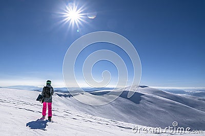 Snowboarder woman with snowboard in hand on mountain top. Winter freeride snowboarding Stock Photo