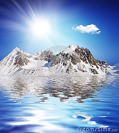 Snowcovered high mountain besides a lake with nice Stock Photo