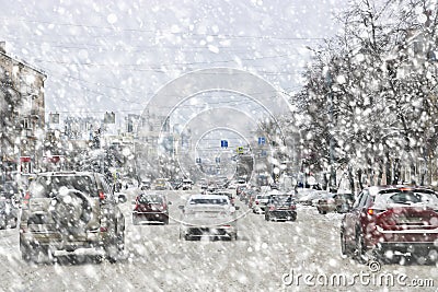 Snowfall and blizzard in city, cars on slippery road, poor visibility, dangerous situation on the road Stock Photo